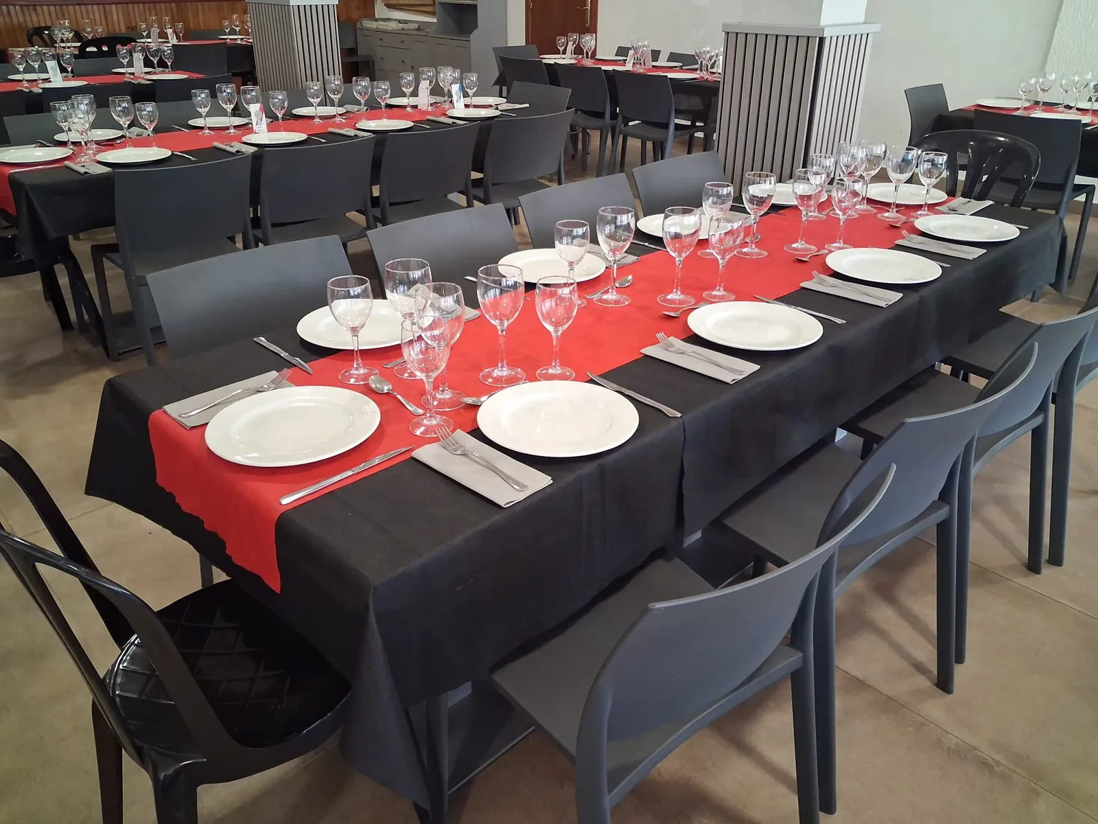 Mesa larga del Restaurante Elena con mantel negro, camino rojo y copas